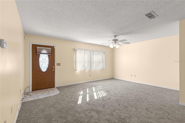 carpeted entryway with ceiling fan, a healthy amount of sunlight, and a textured ceiling