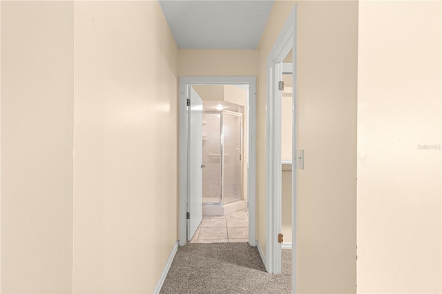 corridor with a textured ceiling and light colored carpet