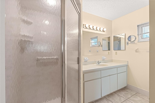 bathroom featuring tile patterned floors, a shower with door, vanity, and a textured ceiling