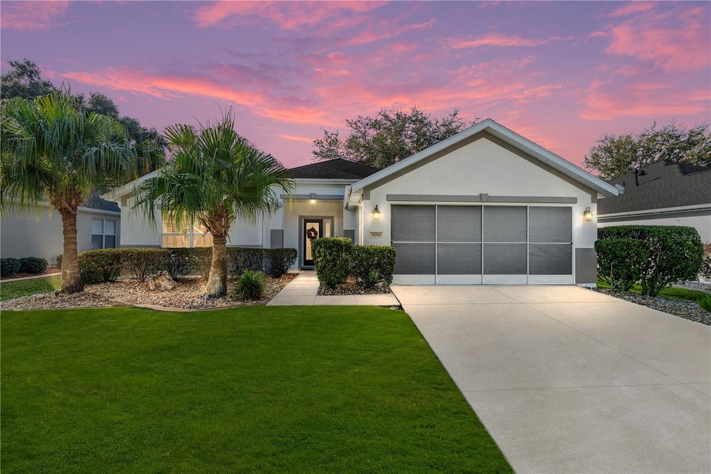 single story home featuring a lawn and a garage