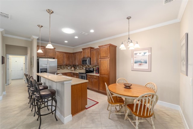 kitchen with light tile patterned flooring, a center island, stainless steel appliances, pendant lighting, and decorative backsplash