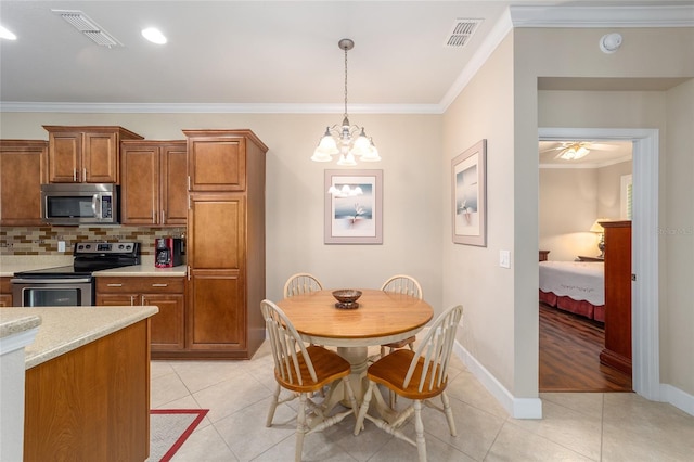 kitchen featuring appliances with stainless steel finishes, ornamental molding, pendant lighting, and ceiling fan with notable chandelier