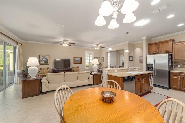 tiled dining space with crown molding, sink, and ceiling fan with notable chandelier