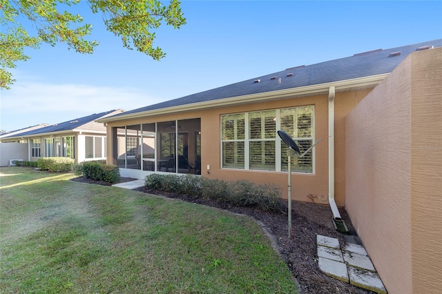 rear view of property featuring a sunroom and a lawn