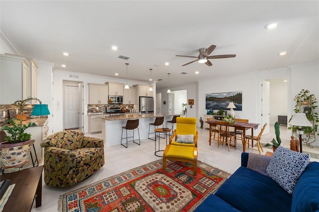 tiled living room with ceiling fan, ornamental molding, and sink