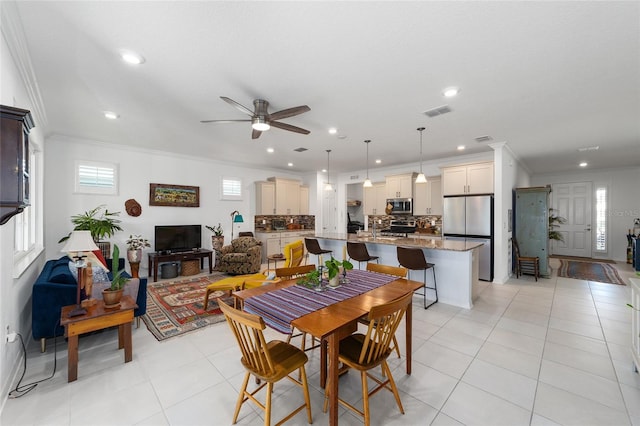 tiled dining area featuring crown molding and ceiling fan