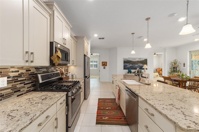 kitchen with appliances with stainless steel finishes, decorative light fixtures, sink, and backsplash