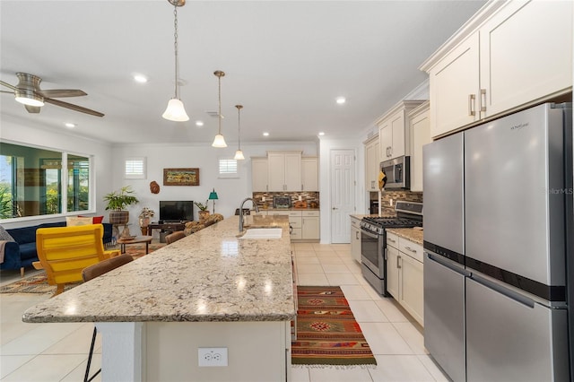 kitchen featuring sink, a spacious island, appliances with stainless steel finishes, and decorative light fixtures