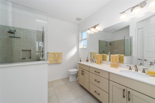 bathroom with vanity, a tile shower, toilet, and tile patterned flooring