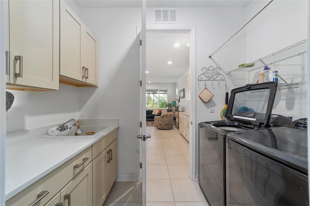 laundry area with sink, independent washer and dryer, light tile patterned floors, and cabinets