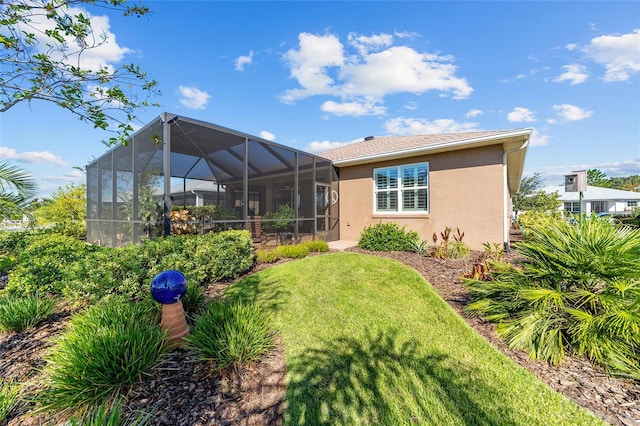 rear view of house with a lawn and a lanai