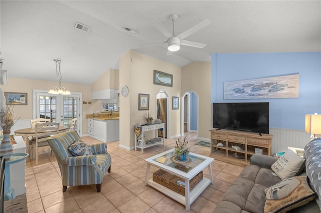 tiled living room with ceiling fan with notable chandelier and lofted ceiling