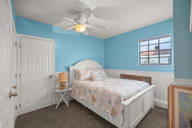 carpeted bedroom with wood walls, a textured ceiling, and ceiling fan