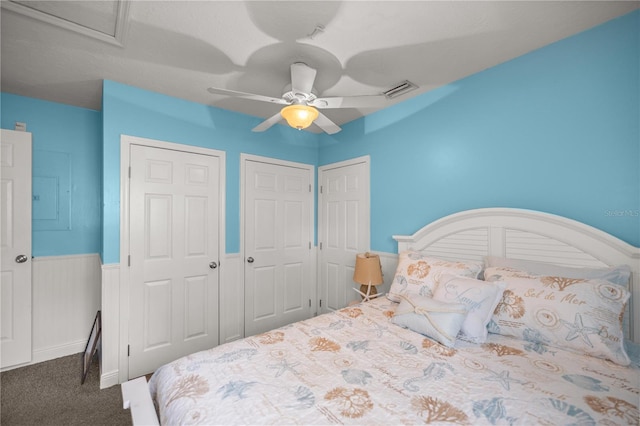 bedroom featuring carpet, ceiling fan, and two closets