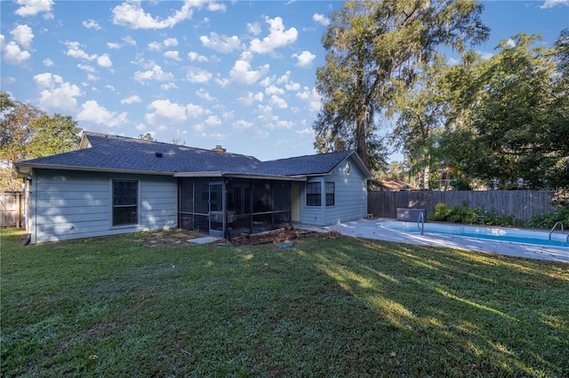 rear view of house with a fenced in pool, a sunroom, and a yard