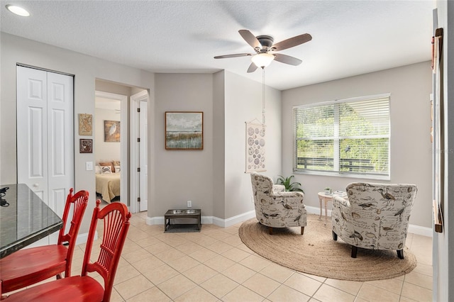 living area featuring ceiling fan, a textured ceiling, and light tile patterned floors