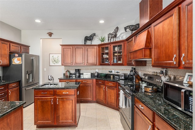 kitchen with custom range hood, dark stone counters, sink, light tile patterned floors, and appliances with stainless steel finishes