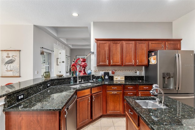 kitchen with appliances with stainless steel finishes, dark stone countertops, sink, and a textured ceiling