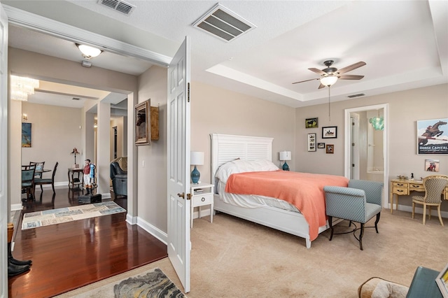 carpeted bedroom featuring a tray ceiling and ceiling fan