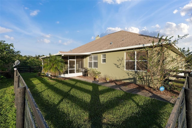 back of house featuring a sunroom and a lawn