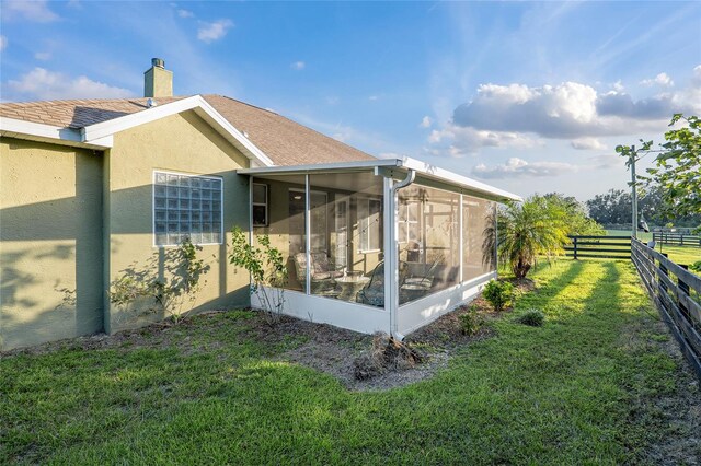 view of property exterior with a yard and a sunroom