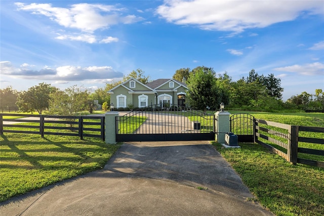 view of gate with a rural view and a lawn