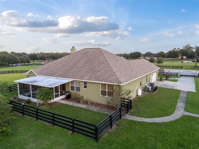 rear view of property featuring a rural view, a yard, and a sunroom