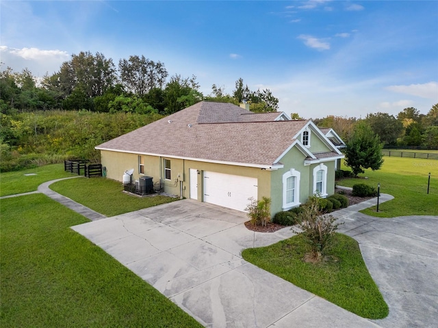 ranch-style home with a garage, a front lawn, and central AC unit