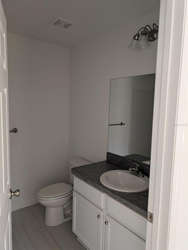 bathroom featuring vanity, hardwood / wood-style floors, and toilet