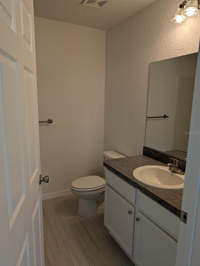 bathroom featuring vanity, toilet, and a textured ceiling