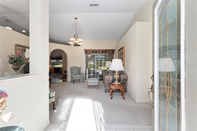 carpeted foyer entrance with vaulted ceiling and a chandelier