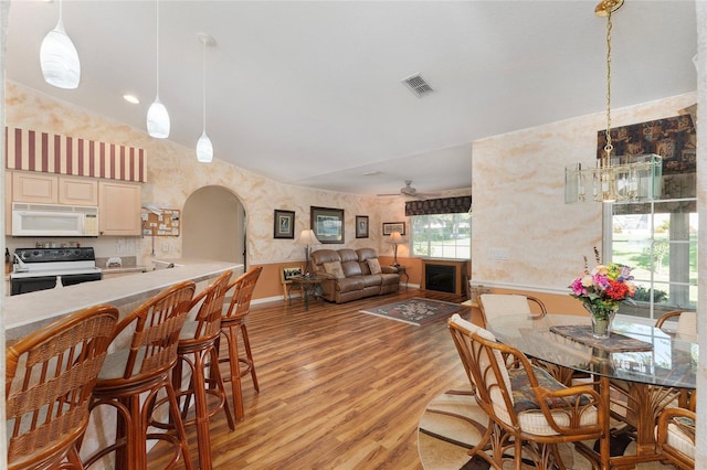 dining room with light hardwood / wood-style floors, ceiling fan with notable chandelier, and vaulted ceiling