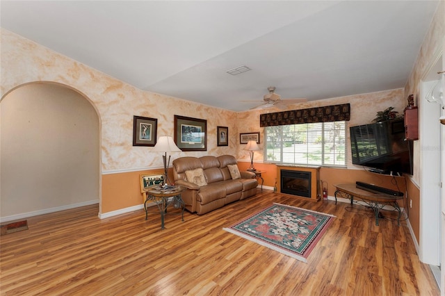 living room with ceiling fan, wood-type flooring, and lofted ceiling