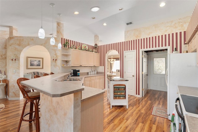 kitchen featuring a breakfast bar, kitchen peninsula, lofted ceiling, pendant lighting, and light hardwood / wood-style flooring