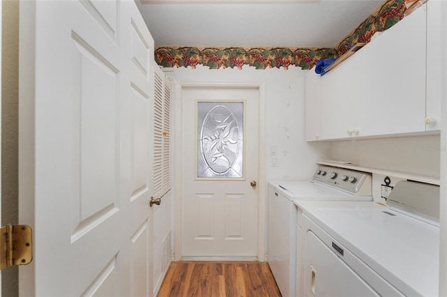 clothes washing area with washing machine and clothes dryer, light wood-type flooring, and cabinets