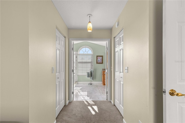 hall featuring a textured ceiling and light colored carpet