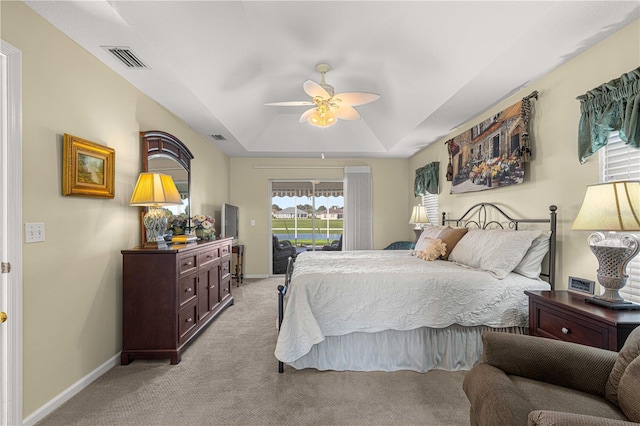 bedroom featuring a raised ceiling, light carpet, and ceiling fan