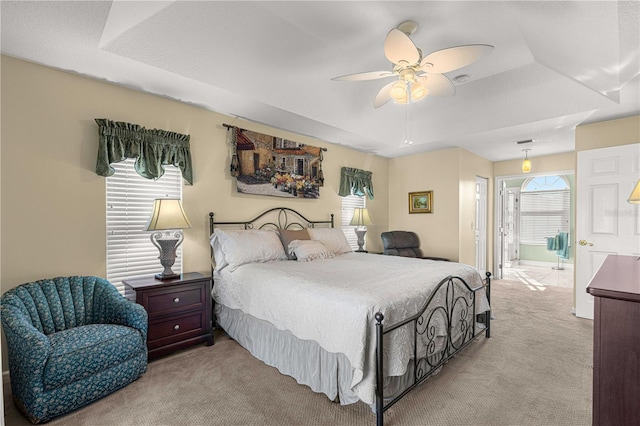 carpeted bedroom with ensuite bathroom, ceiling fan, and a raised ceiling