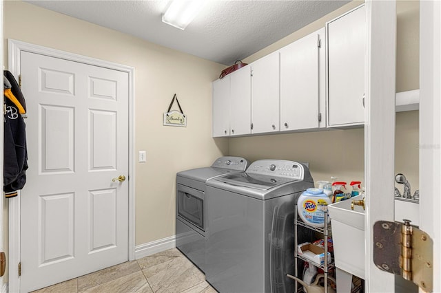 laundry room with cabinets, a textured ceiling, sink, and washing machine and dryer