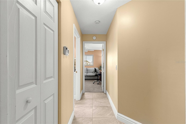 corridor featuring a textured ceiling and light tile patterned floors