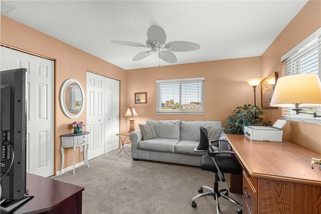 home office featuring a wealth of natural light, a textured ceiling, light colored carpet, and ceiling fan