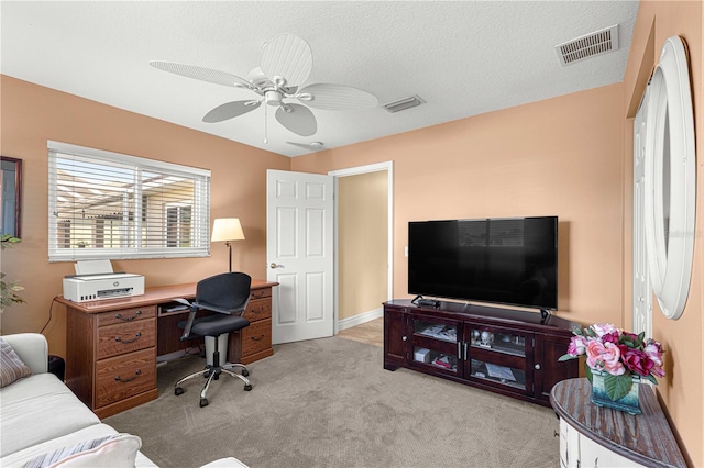 carpeted home office with ceiling fan and a textured ceiling