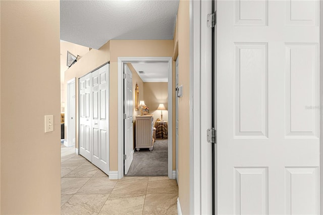 hall featuring a textured ceiling and light colored carpet