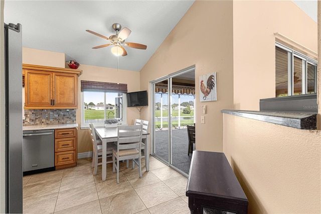 kitchen featuring decorative backsplash, ceiling fan, stainless steel dishwasher, vaulted ceiling, and light tile patterned flooring