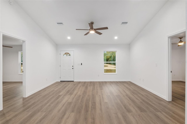 unfurnished living room featuring ceiling fan, vaulted ceiling, and light wood-type flooring