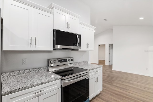 kitchen with light stone counters, white cabinetry, appliances with stainless steel finishes, and lofted ceiling