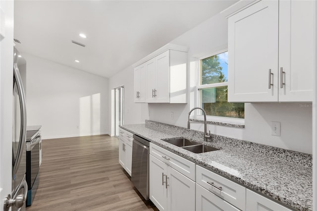 kitchen featuring white cabinetry, stainless steel appliances, light stone counters, and sink