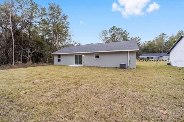 back of property featuring a lawn and central air condition unit