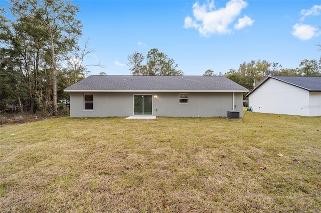 rear view of property featuring a lawn and central air condition unit