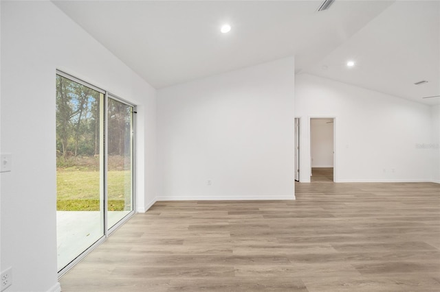 empty room with light hardwood / wood-style floors, a wealth of natural light, and lofted ceiling